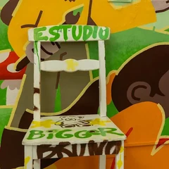 Silla pintada "Estudio BiGGeR" sobre el mural del taller